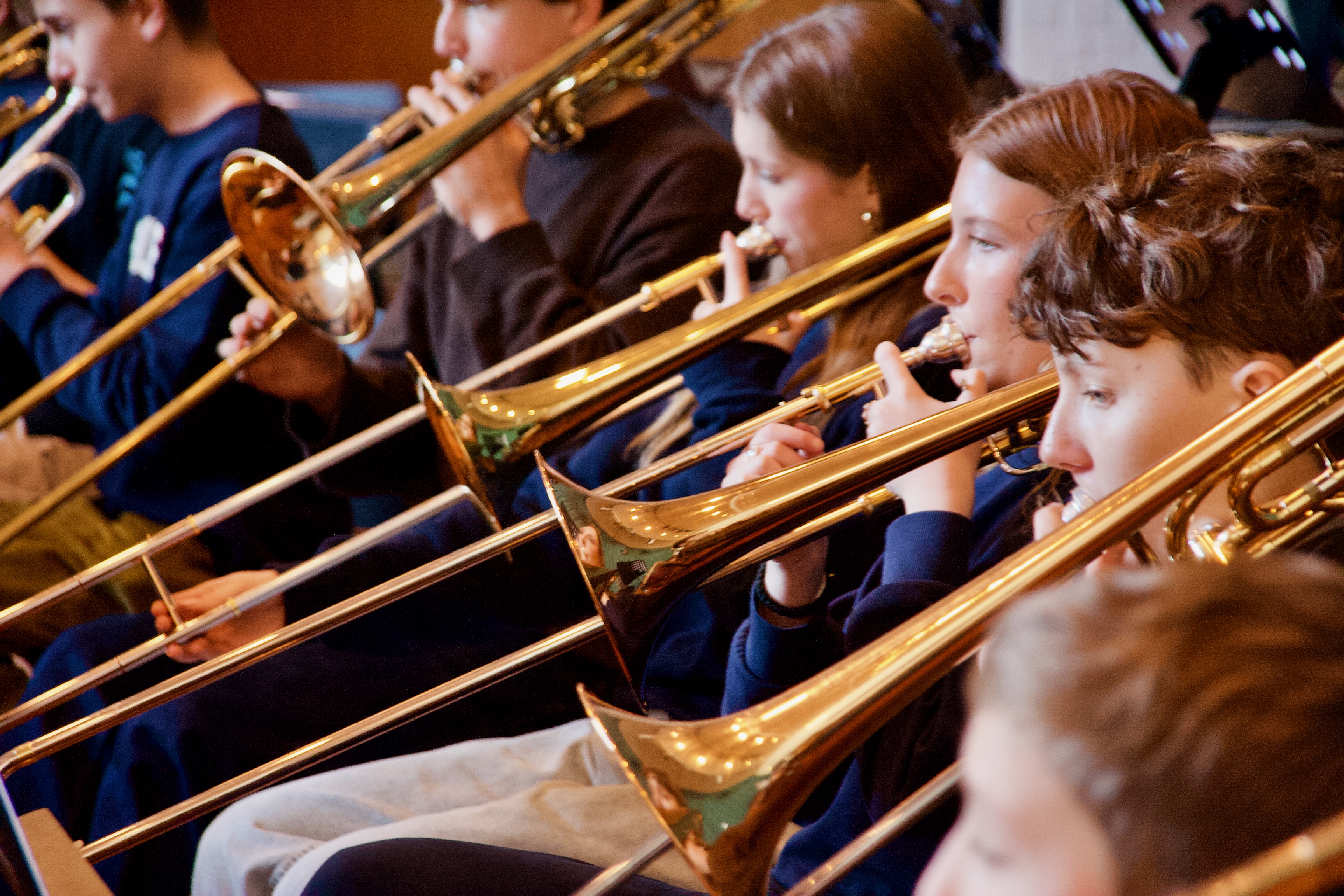 Unge sidder på række med deres blæserinstrument og spiller til koncert